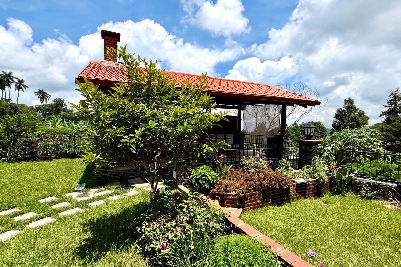 La ramada de teja entre palmeras y cielo abierto, en el punto más alto del jardín